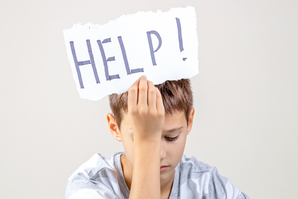 Sad tired frustrated boy holding torn paper card with word Help. Learning difficulties, kid emotions